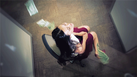 Gif. Woman spinning in circles on an office chair while dollar notes rain down