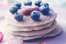 stack of pancakes with strawberries, blueberries and sugar