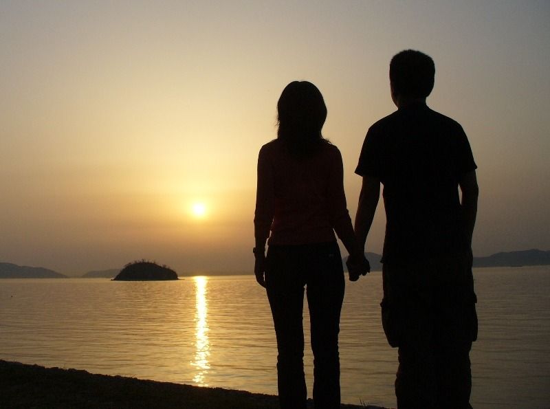 couple holding hands on a beach at sunset