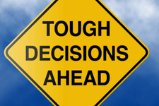 Yellow warning sign saying "tough decisions ahead"