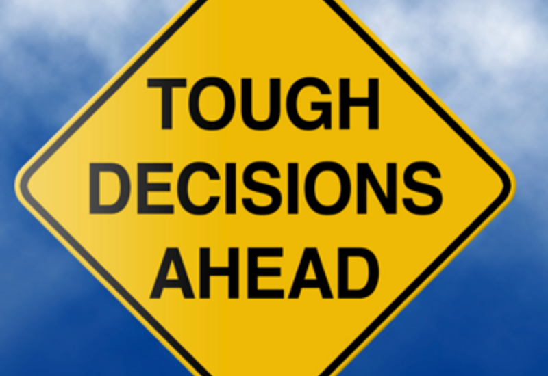 Yellow warning sign saying "tough decisions ahead"