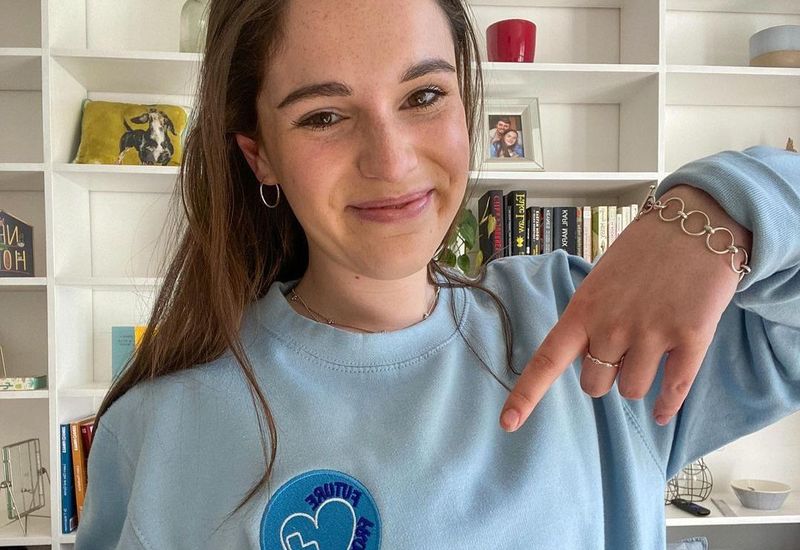 Tash smiling and pointing to the emblem on her jumper that reads "Future Frontline", the name of the organisation she founded