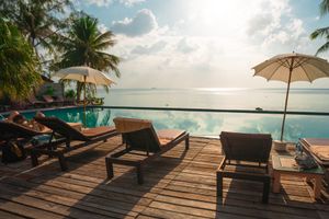 Sun loungers at the edge of a pool in an idyllic tropical holiday resort