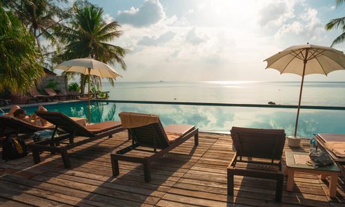 Sun loungers at the edge of a pool in an idyllic tropical holiday resort