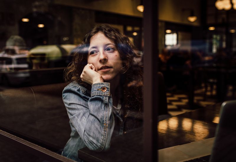 Woman waiting, looking through a cafe window