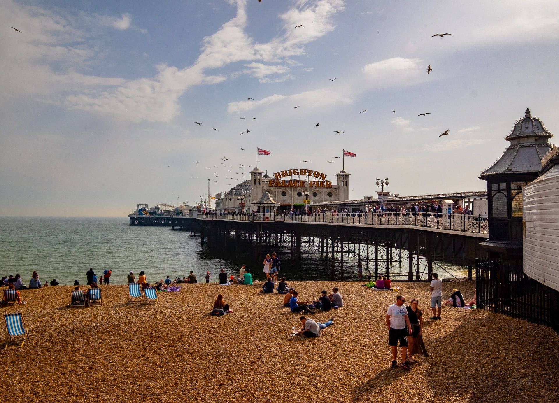 Picture of a busy Brighton beach with the Palace Pier in the middle of the shot