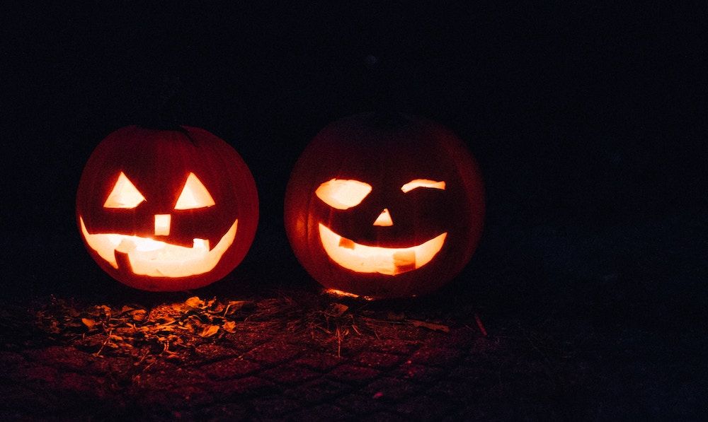 Two Jack-o'-Lanterns lit up in the dark.