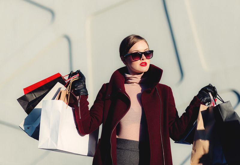 Woman in faux fur jacket with loads of shopping bags of different colours