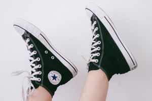 A Person wearing Converse Chuck Taylors putting their feet in the air.