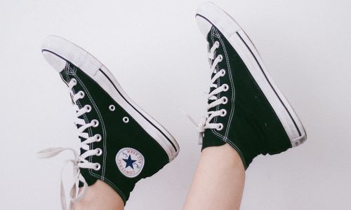A Person wearing Converse Chuck Taylors putting their feet in the air.