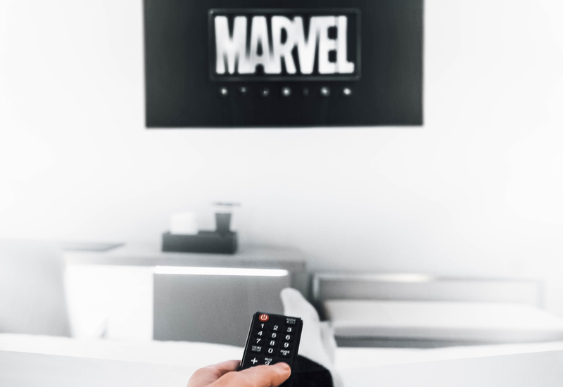 A remote being pointed at a screen with the Marvel logo on it