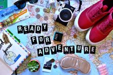 Various travel accessories on top of a map and the words "Ready for adventure"