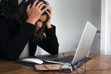 Woman looking stressed sat at a desk with her laptop