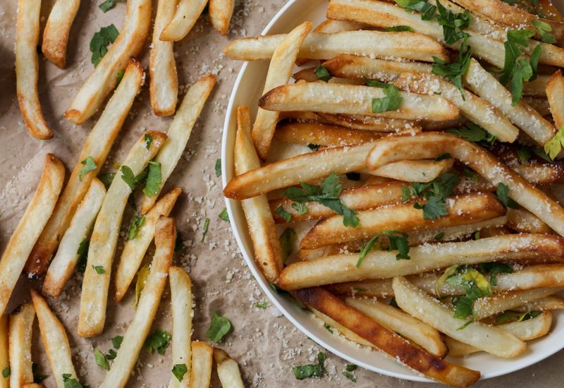 Chips spilling off a plate, seasoned with sea salt and parsely