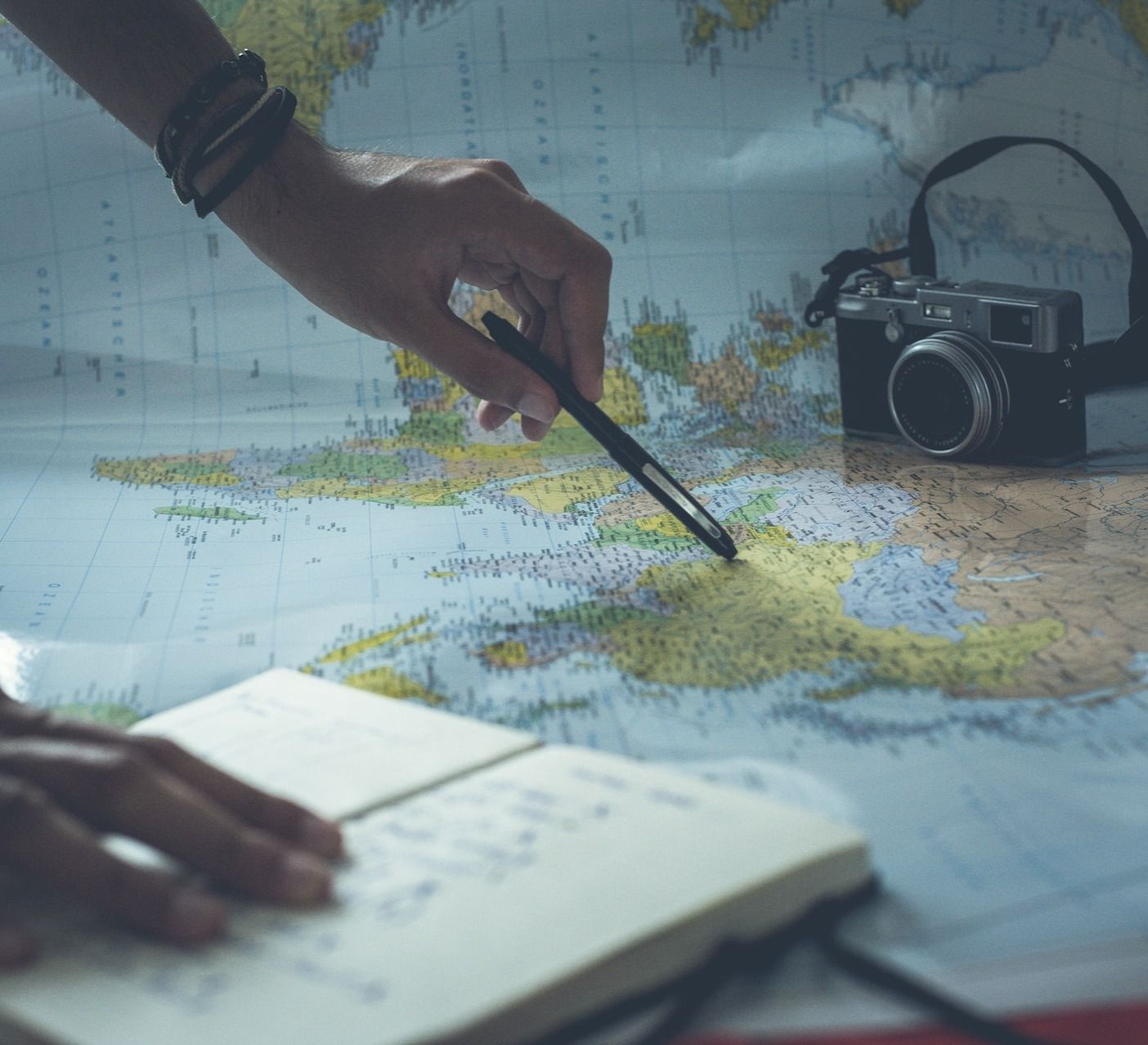 Person planning their travels with a camera, notebook and map