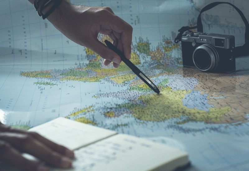 Person planning their travels with a camera, notebook and map