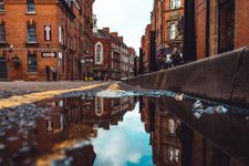 Photo taken from the ground of a street in Leicester, with a reflection in the puddle