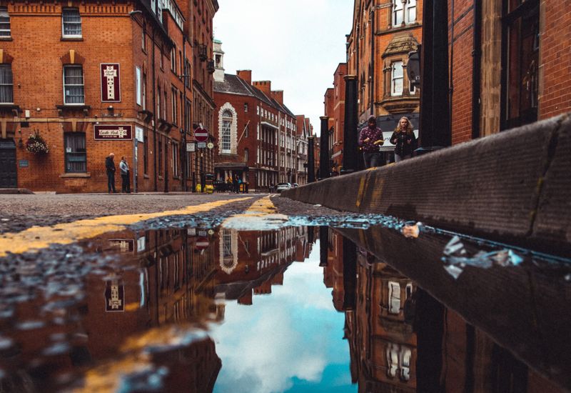 Photo taken from the ground of a street in Leicester, with a reflection in the puddle