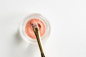 Makeup brush in a pot of pink powder.