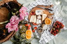 Beautiful picnic spread with fruits - kiwi, orange, and strawberries - and cheeses