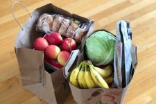 Two paper bags with groceries, including fresh fruit and a packet of bagels