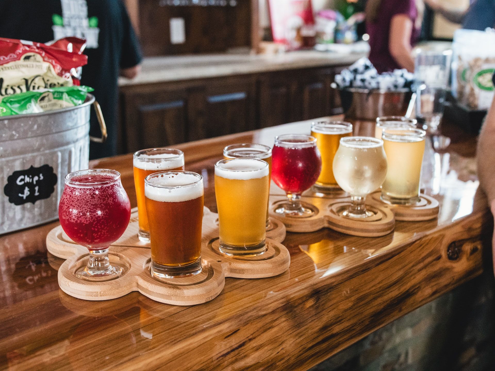 A selection of different coloured ciders poured in glasses and laid out across a bar