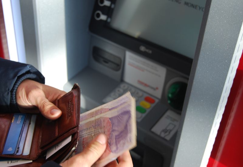 Person holding cash they have just taken out from an ATM
