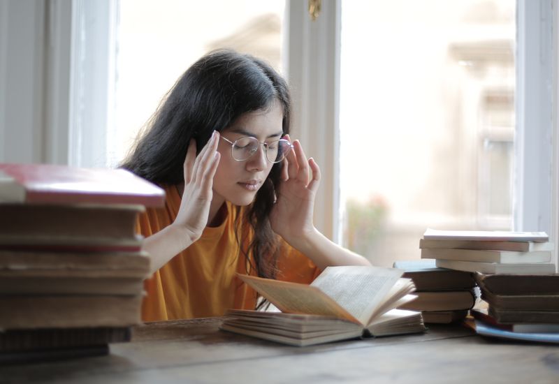 Student stressed surrounded by books