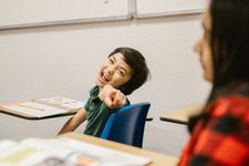 Young boy in classroom pointing and laughing at the camera