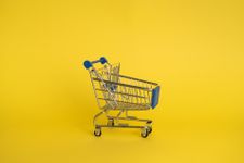 Miniature supermarket trolley in front of a plain yellow background