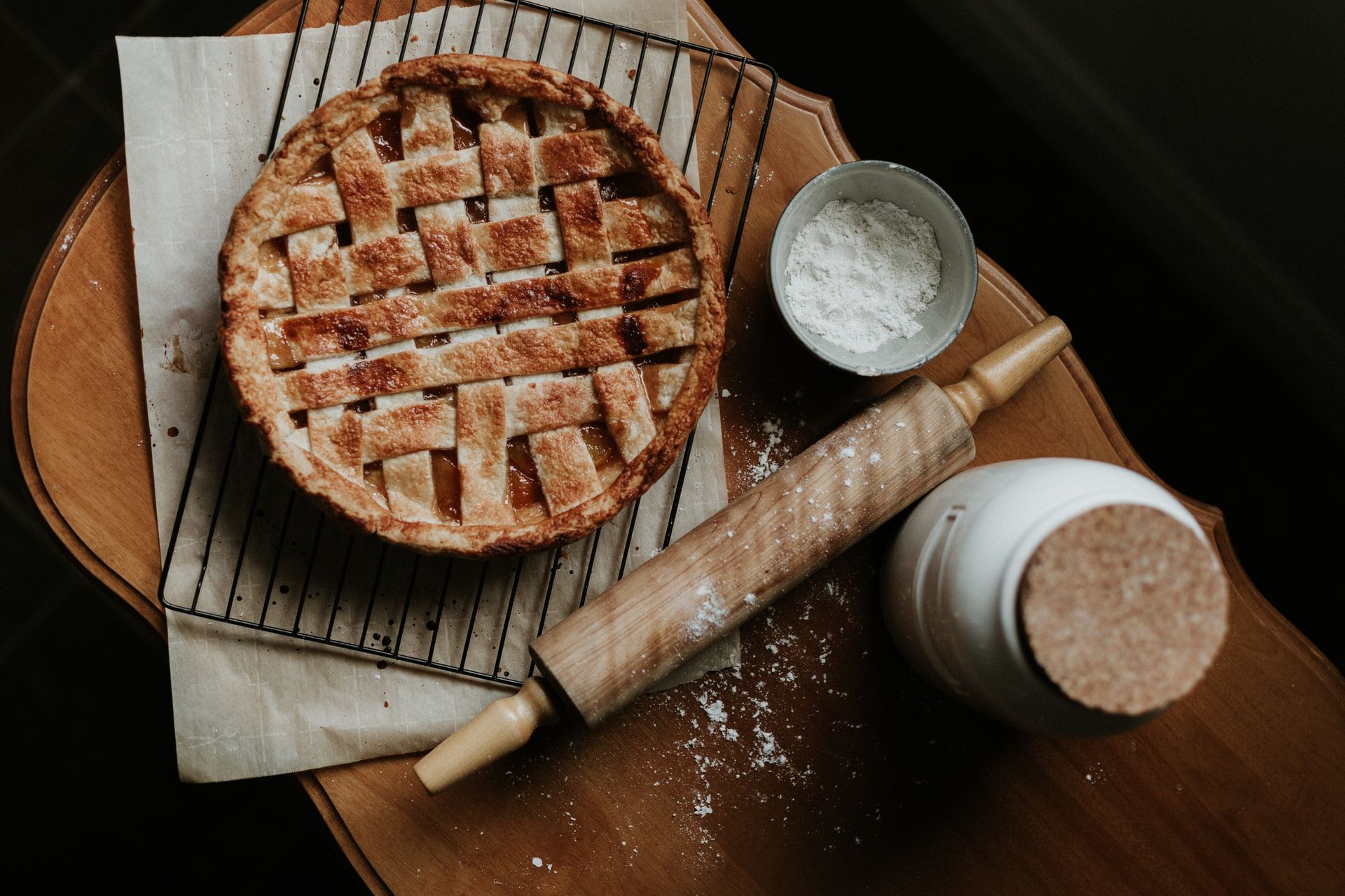 pie on a cooling rack with a jar of flour and a rolling pin