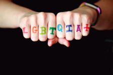 LGBTQIA+ written in rainbow letters across someone's knuckles