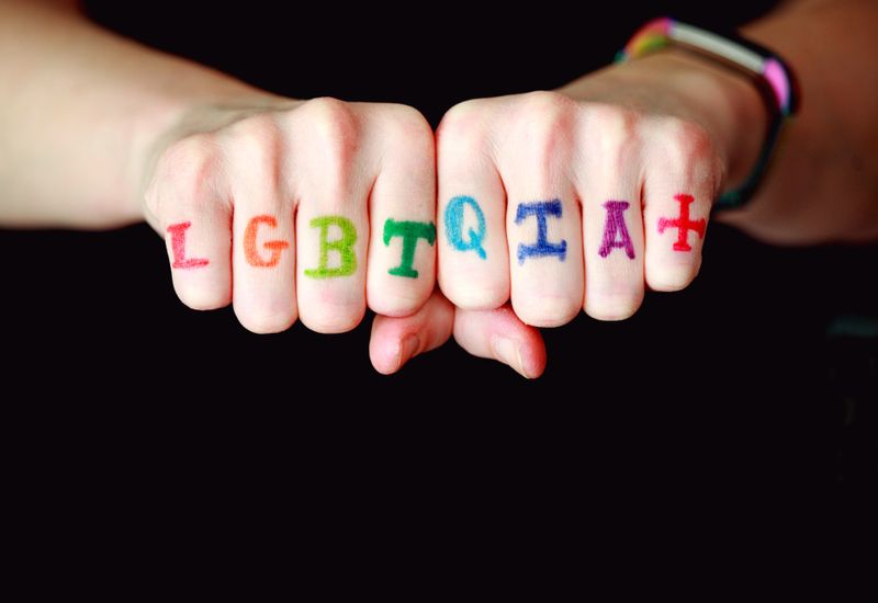 LGBTQIA+ written in rainbow letters across someone's knuckles