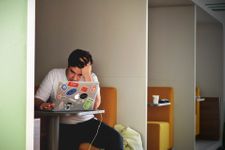 Student sat in a cubicle revising, seemingly stressed