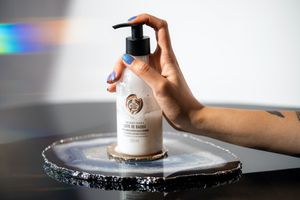 A person with a hand on a pump bottle of a moisturiser from the body shop
