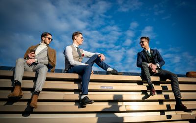 Three stylish men sat on a wall